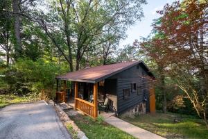 a small black house with a porch on a road at The Woodsman Lodge in Eureka Springs