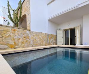 a swimming pool in a house with a stone wall at Villetta Tina Private Pool - Torre Pali in Torre Pali