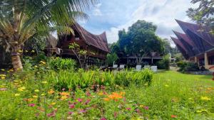 a garden with flowers in front of a building at Leokap Homestay in Tuktuk Siadong +13 photos
