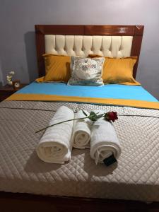 a bed with two rolled towels and a rose on it at Appartement Dan'L Ngousso in Yaoundé