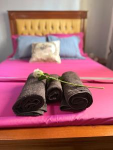 a bed with pink sheets and black towels on it at Appartement Dan'L Ngousso in Yaoundé