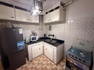 a kitchen with white cabinets and a black refrigerator at Appartement Dan'L Ngousso in Yaoundé
