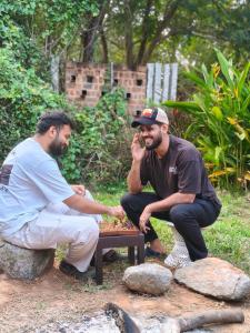 two men sitting around a picnic table talking on a cell phone at Zomad Hostels Pondicherry, Auroville Road in Auroville