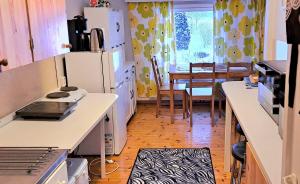 a kitchen with white appliances and a dining room with a table at Rantakorpi Farm in Niemisjärvi