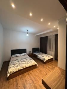 two beds in a room with wooden floors at Central View Prishtina in Prishtinë
