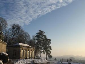 a building with snow on the ground next to a tree at Château d'Hodebert in Saint-Paterne-Racan