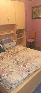 an empty bed in a room with a chair at Chez NONO in Ruffec