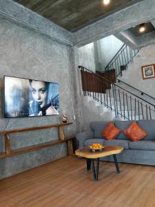 a living room with a couch and a tv on a wall at Loft Life Pool villa in Ban Huai Yai