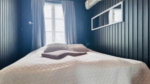 a bedroom with a bed with blue walls and a window at Savupirtti 1819 in Pudasjärvi