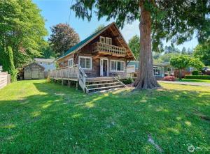 a log home with a tree in the yard at Charming and cozy cottage at Maple Beach in Point Roberts