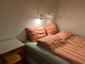 a bedroom with a bed with orange sheets on it at Sentralt og koselig in Kristiansand