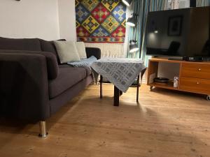 a living room with a couch and a table and a tv at Sentralt og koselig in Kristiansand
