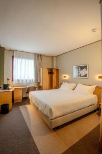 a hotel room with a large bed and a desk at Tulip Inn Turin South in Moncalieri +45 photos
