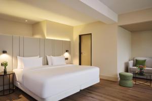 a bedroom with a large white bed and a chair at NH Düsseldorf Königsallee in Düsseldorf