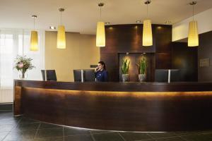 a man talking on a phone at a reception desk at NH Düsseldorf Königsallee in Düsseldorf +26 photos