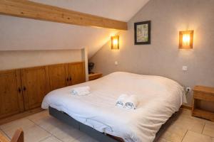 a bedroom with a large white bed with two towels at Hôtel Résidence La Maison par Les Pins Sylvestres Amnéville les Thermes in Amnéville