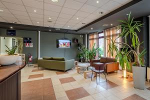 a lobby with a waiting room with plants at Tulip Inn Turin South in Moncalieri