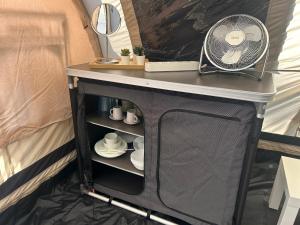 a table with a fan and cups and plates at Bella Tents - Camping Vibes in Marina di Grosseto