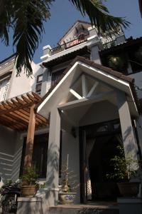 un edificio blanco con una puerta delantera y una palmera en Green CoCo HomeStay, en Hoi An