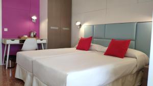 a bedroom with a large white bed with red pillows at Huéspedes Sa Font in Ibiza Town