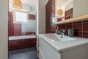 a bathroom with a sink and a tub and red tiles at Le Stanislas 61 - Spacieux & Cosy in Nancy