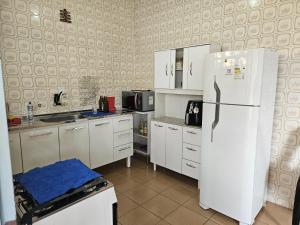 a kitchen with white cabinets and a refrigerator at Casa familiar e espaçosa em Aparecida SP, com 3 quartos in Aparecida