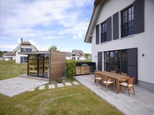 a backyard with a wooden table and a house at Reetland am Meer - LuxusPlus Reetdachvilla mit 4 Schlafzimmern, Außensauna, Loungebereich und Kamin H09 in Dranske