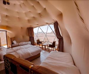 a room with three beds and a large window at Moonlight Luxury Bubble Camp & Jeep Tours in Wadi Rum