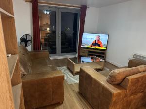 a living room with couches and a flat screen tv at Ganmos Place in Bracknell