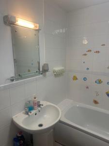 a white bathroom with a sink and a bath tub at Ganmos Place in Bracknell +8 photos