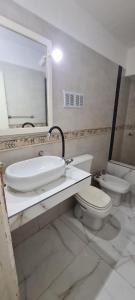 a bathroom with a sink and a toilet and a mirror at Vicco in Pinamar +5 photos