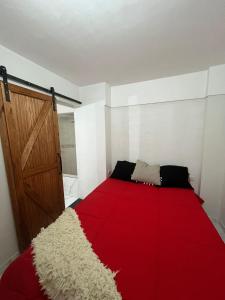 a bedroom with a red bed and a wooden door at Vicco in Pinamar