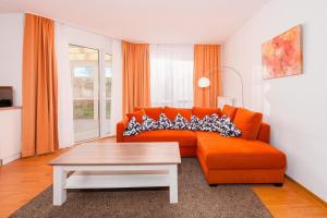 a living room with an orange couch and a coffee table at Strandhaus Lobbe, Sanddorn Nr 3 - Bade- & Saunawelt täglich inklusive in Lobbe
