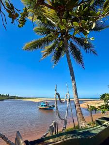 a boat on the water next to a palm tree at Bangalô 12 in Porto Seguro