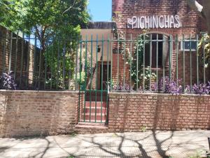 a brick fence with a gate in front of a building at Alojamiento Pichinchas in Paso de los Libres