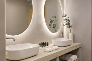a bathroom with two sinks and a large mirror at Alaia Boutique houses in Batsi +40 photos