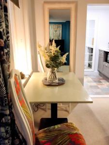 a dining room table with a vase of flowers on it at Beachfront Studio Apartment in Felixstowe