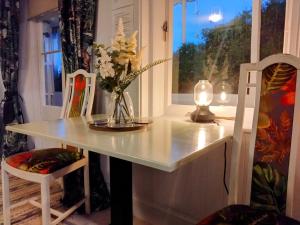 a white table with a vase of flowers on it at Beachfront Studio Apartment in Felixstowe