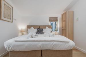 a bedroom with a bed with white sheets and pillows at Rusheen Cottage in St. Andrews