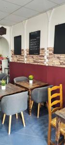 a restaurant with tables and chairs and a chalkboard on the wall at Hôtel Le Poussin Rouge in Saint-Sauveur-sur-Tinée