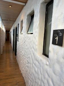 a hallway with a white wall with windows at Onda Studios Apê Completo - Vista Linda e Sesc Bertioga - Ar Condicionado in Bertioga
