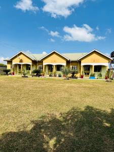 a large yellow house with a large yard at Ekinot homes in Lira