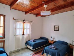 a bedroom with two beds and a wooden ceiling at La Colorada Hostal in Tilcara