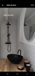 a bathroom with a black bath tub on a wooden table at Chez madame Hulotte in Saint-Nazaire