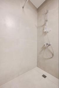a white bathroom with a shower with a hose at Gzira Getaway in Il-Gżira +28 photos