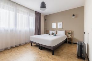 a bedroom with a large white bed and a window at Appart'City Confort Amiens Gare in Amiens