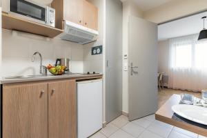 a kitchen with a sink and a microwave at Appart'City Confort Amiens Gare in Amiens