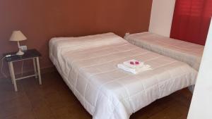 two beds in a room with a table with a lamp at Hotel Corona del inca in Vinchina