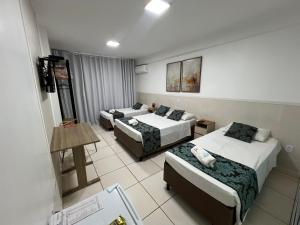 a hotel room with three beds and a table at Max Hotel in Brasília
