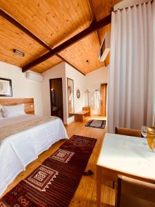 a bedroom with a bed and a table and a desk at Suítes Ad`vinho in Lavras Novas